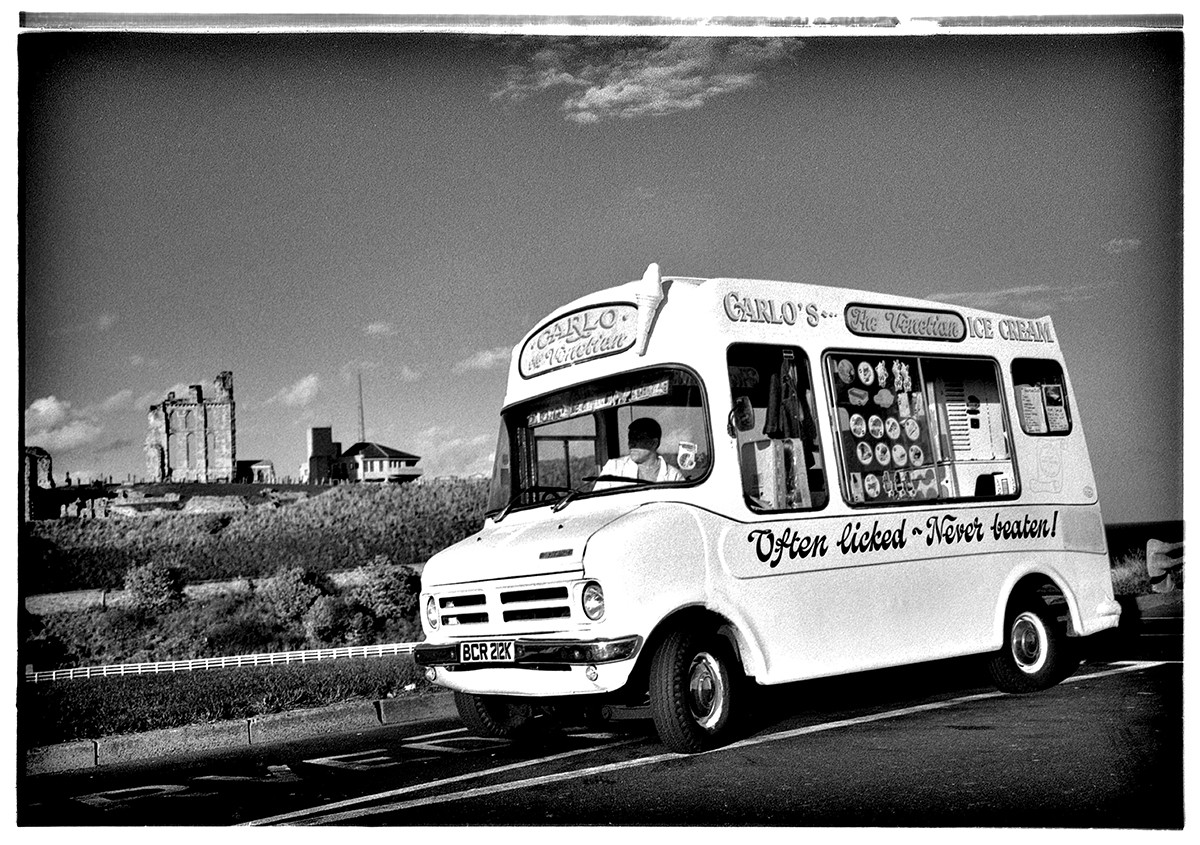 Carlo's ice cream van parked at Tynemouth with the Priory ruins visible in the background — Often Licked, Never Beaten